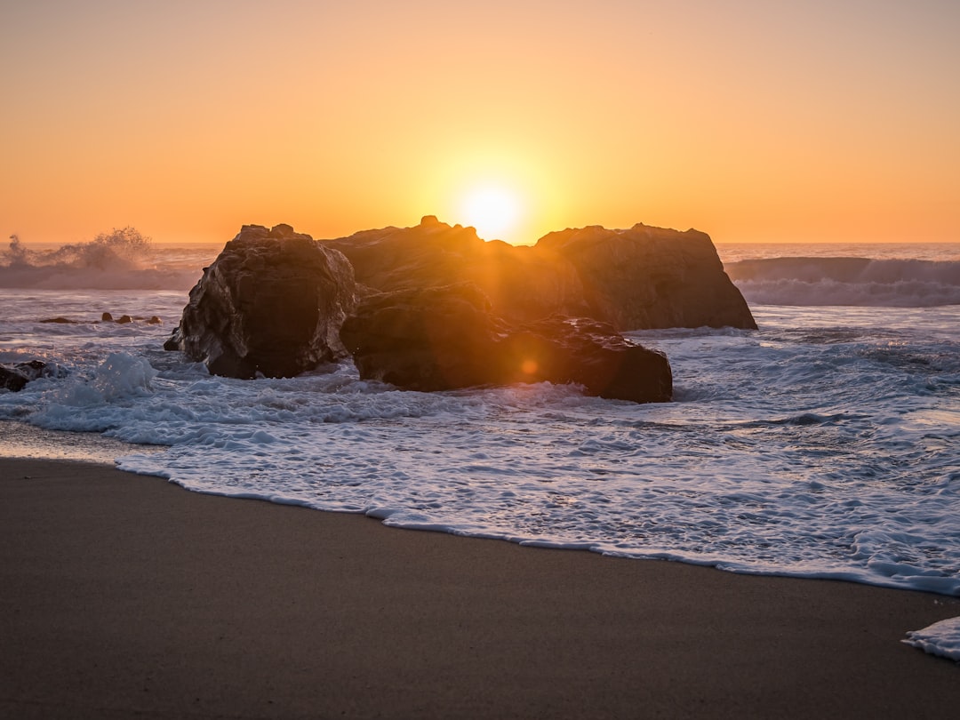 brown rock formation on sea during sunset