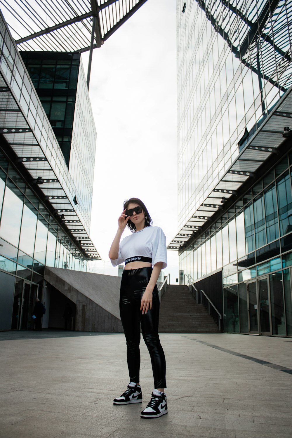 woman in white shirt and black pants standing on gray concrete floor