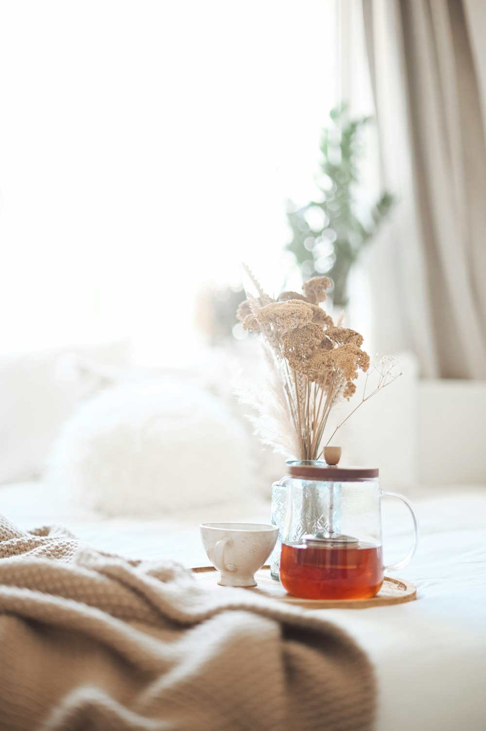 Tasse en verre transparent avec un liquide brun sur une table blanche