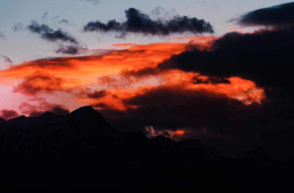 silhouette of mountain under cloudy sky during daytime