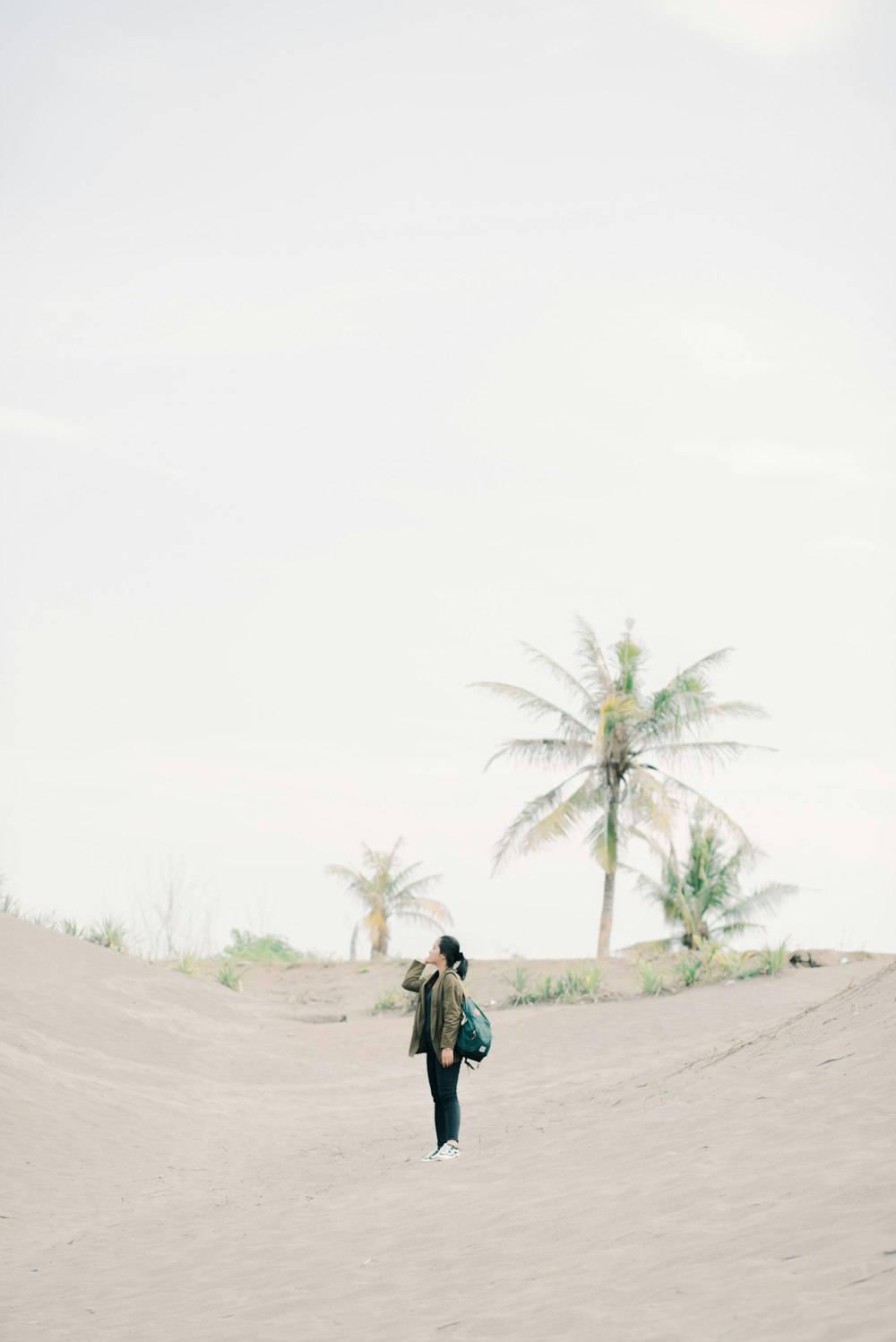 a person walking in the sand with a backpack