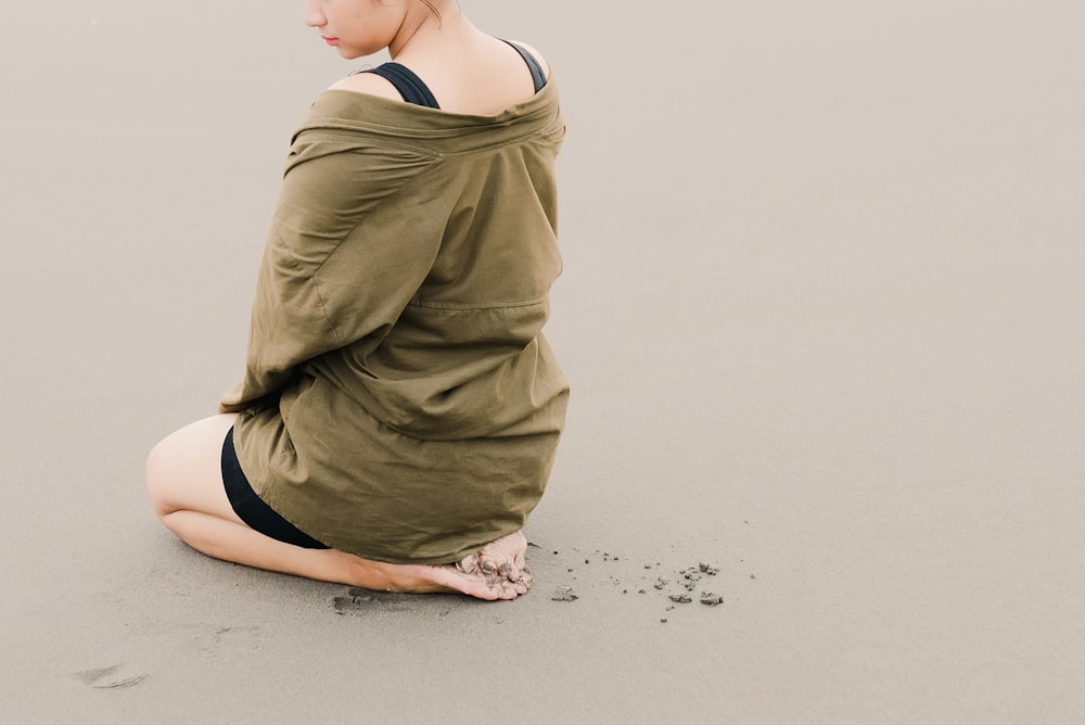 a woman sitting on the beach in a dress