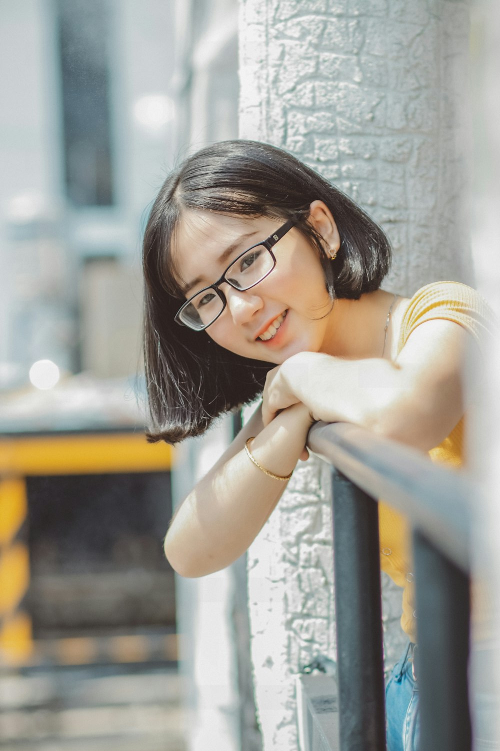 woman in black framed eyeglasses leaning on blue metal railings