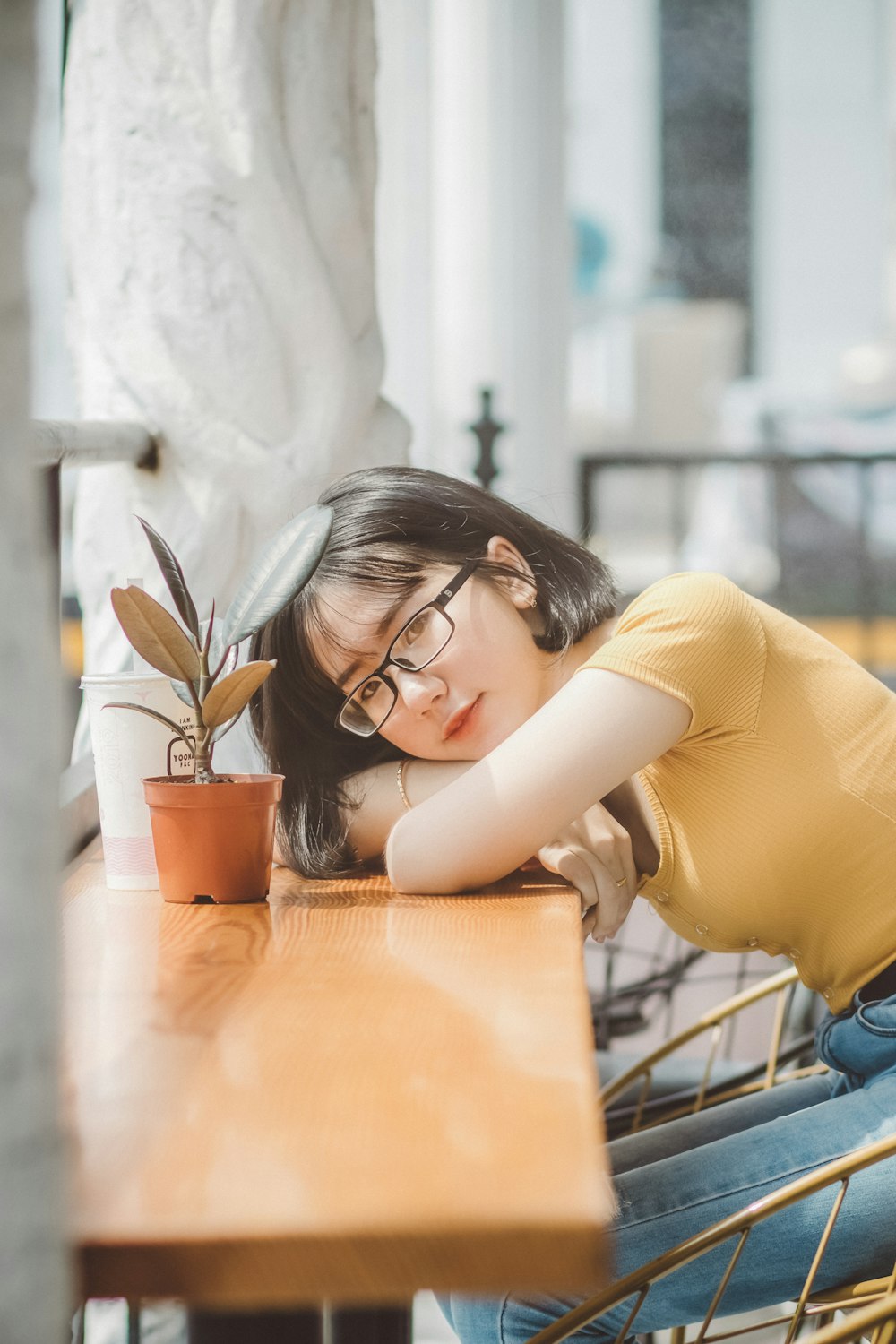 woman in yellow long sleeve shirt sitting by the table