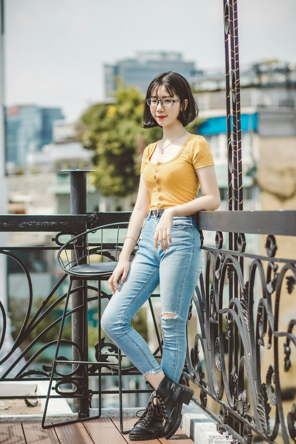 woman in yellow shirt and blue denim jeans sitting on black metal railings