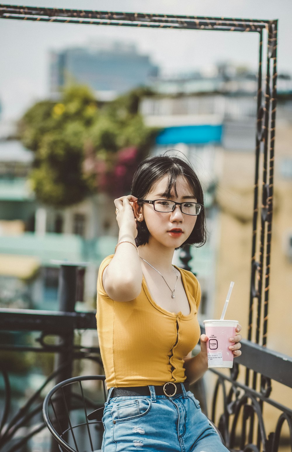 woman in yellow tank top holding white disposable cup