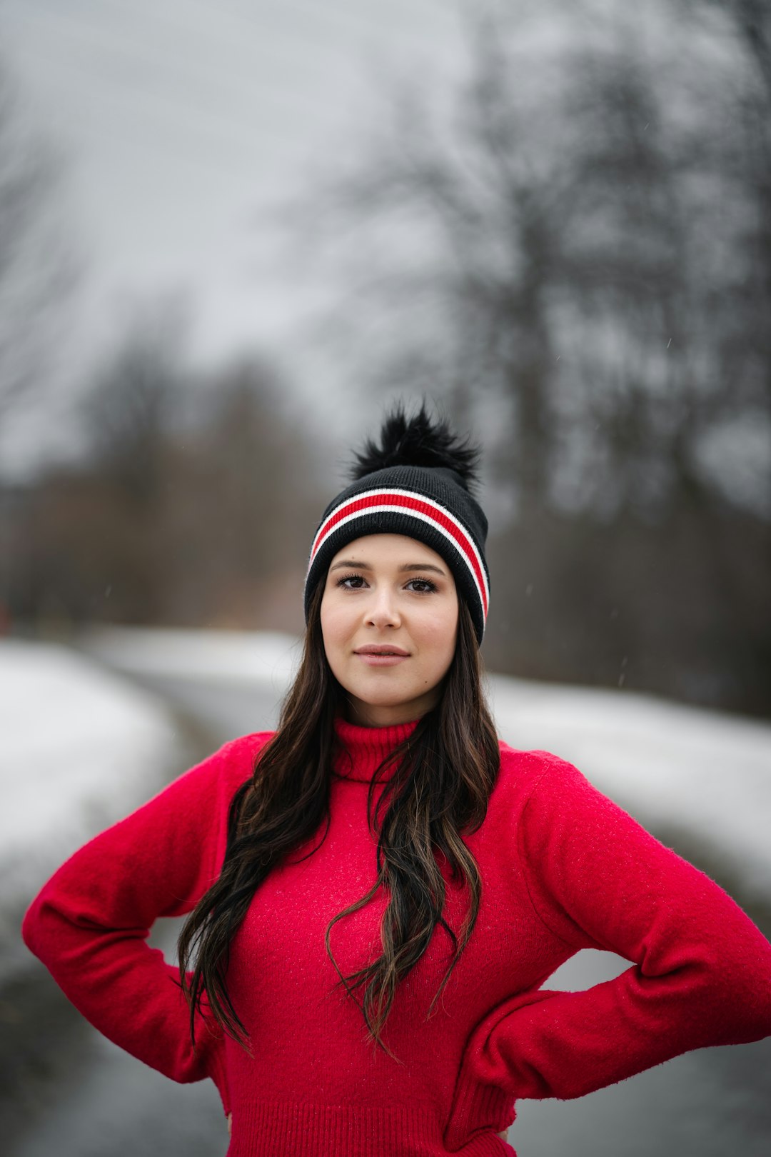 woman in red hoodie standing on snow covered ground during daytime