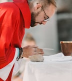 man in red long sleeve shirt holding brown ceramic mug