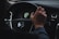A person is gripping the steering wheel of a car with the Volvo logo clearly visible in the center. The dashboard is partially visible, displaying a speedometer and other controls. The hand on the wheel appears relaxed, suggesting a calm driving environment.