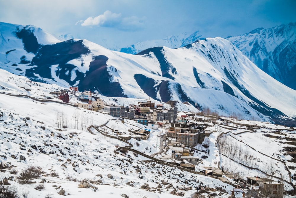 case bianche e marroni sulla montagna coperta di neve durante il giorno