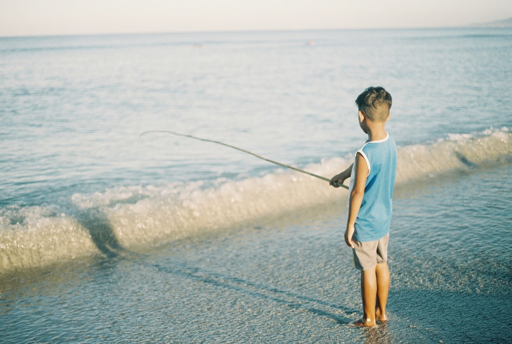 homme en t-shirt à col rond blanc et short marron pêchant sur la mer pendant la journée