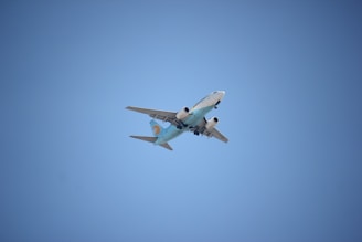 white and blue airplane flying in the sky