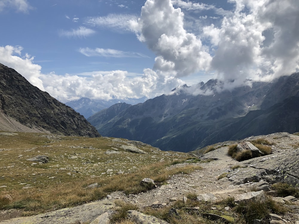 montagnes vertes et brunes sous des nuages blancs et un ciel bleu pendant la journée