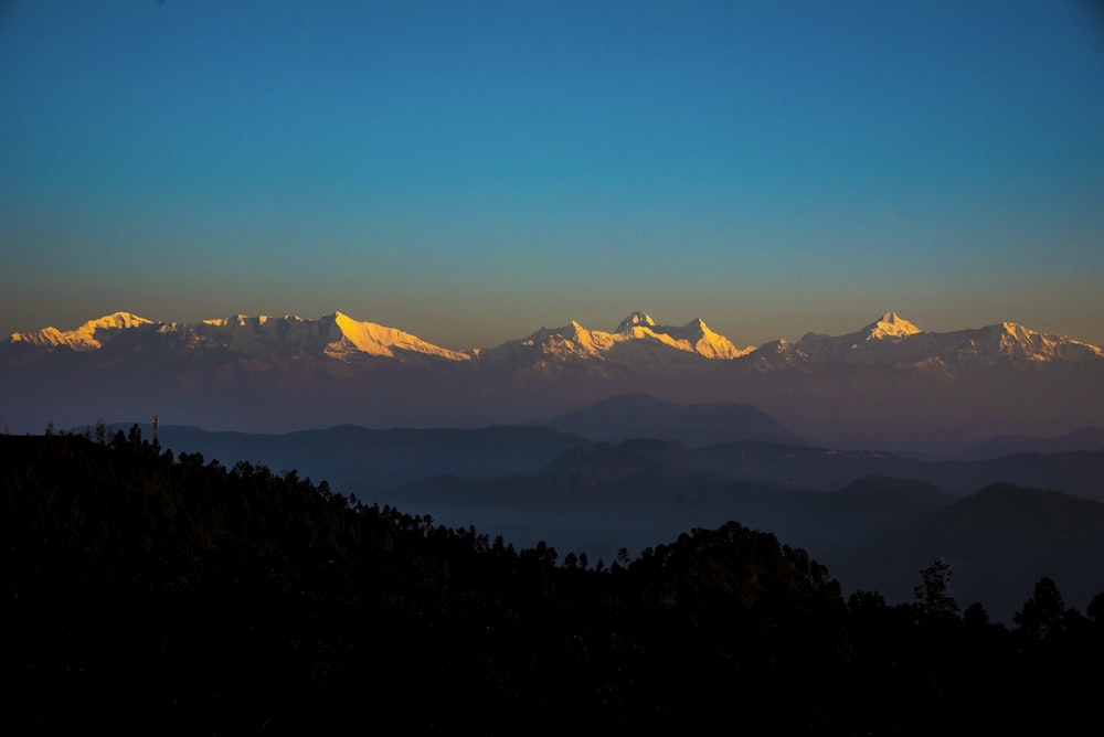 silhouette of trees and mountains during sunset