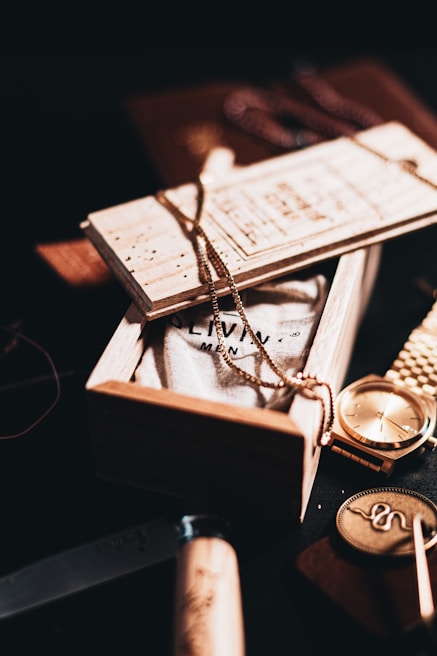 silver round analog watch on brown wooden box