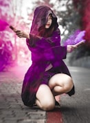 woman in purple dress sitting on gray concrete floor