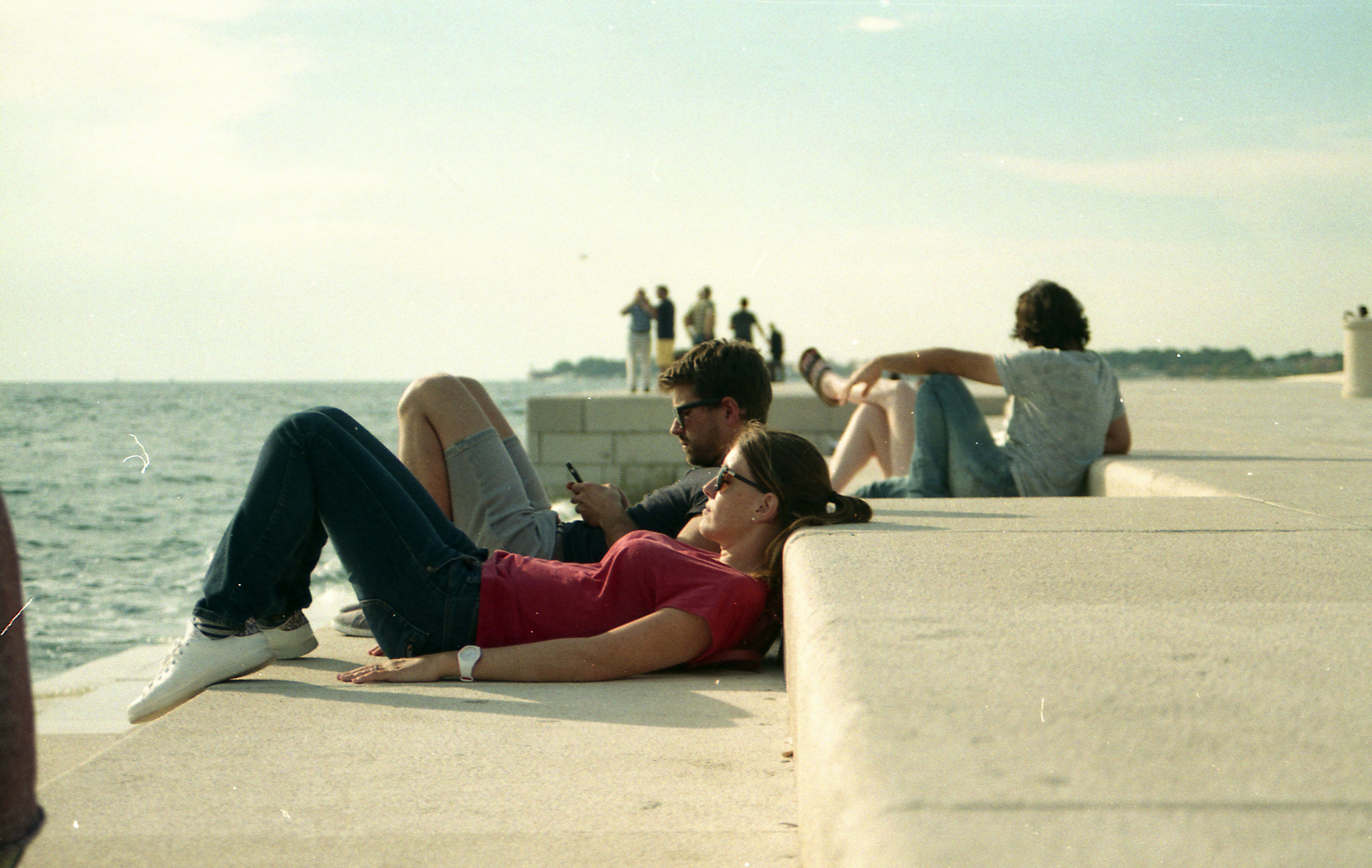 3 women sitting on concrete bench during daytime