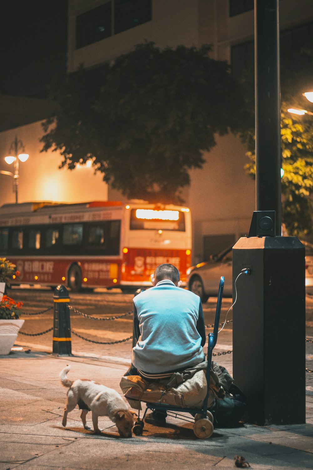 man in blue hoodie sitting on chair near road during night time