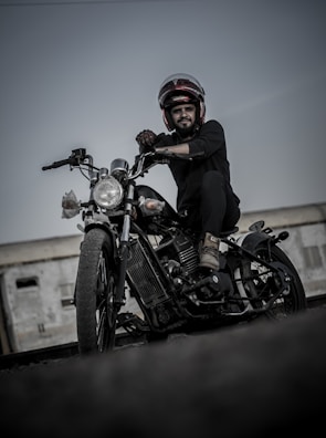 A candid shot of a biker adjusting their helmet beside a classic chopper.