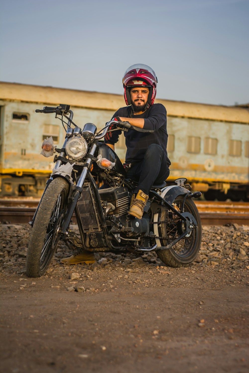 Frau in schwarzer Jacke und rotem Helm fährt schwarzes Motorrad