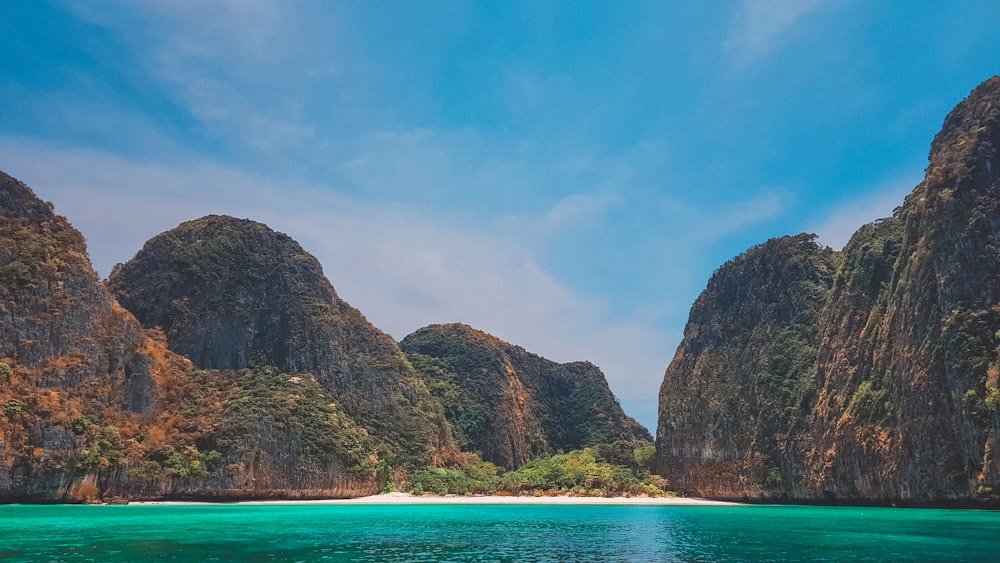 brown and green mountain beside body of water during daytime