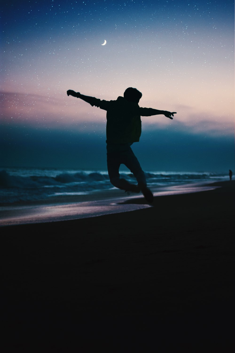 Silhouette eines Mannes, der nachts am Strand springt