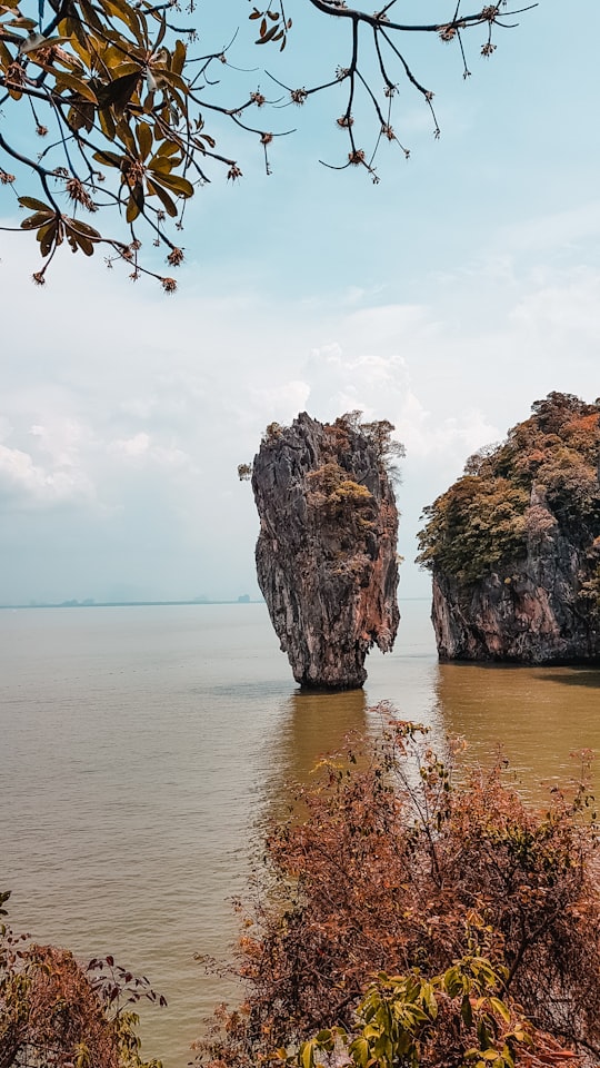brown rock formation on sea under white clouds during daytime in Ao Phang-nga National Park Thailand