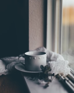A serene image of a teacup placed on a rainy window sill.