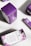 Packages of premium hemp softgels are arranged on a surface. The boxes are predominantly purple with white panels and floral designs. The front of the packaging displays the product name, 'Pure Tranquility', and a brief description of the benefits.