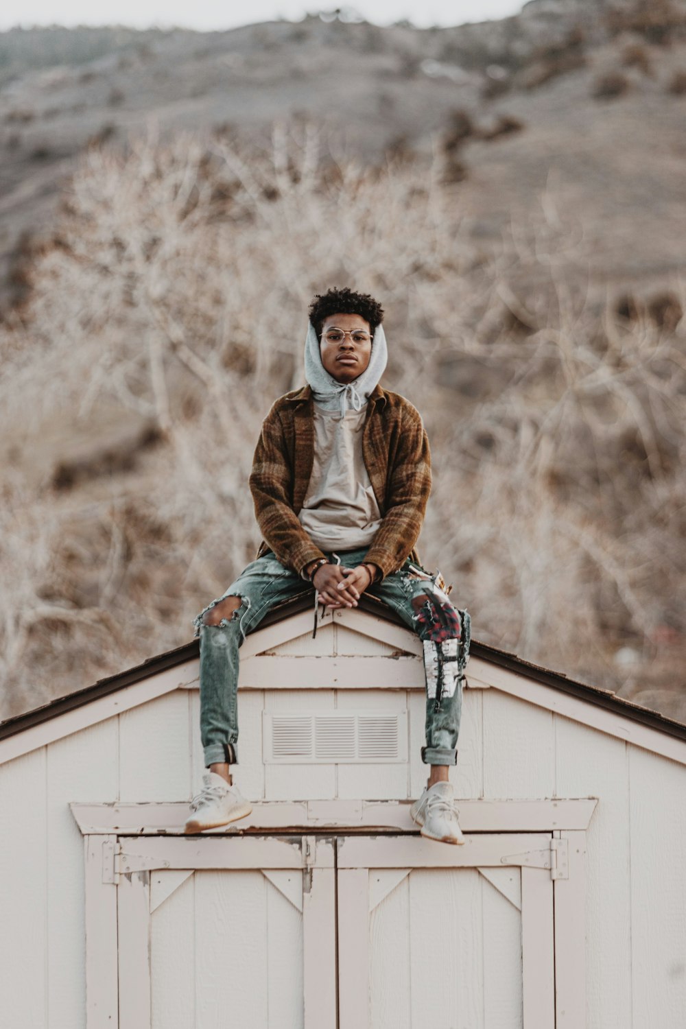 man in brown jacket sitting on gray concrete wall during daytime