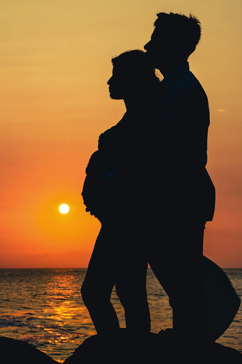 silhouette of man and woman kissing during sunset