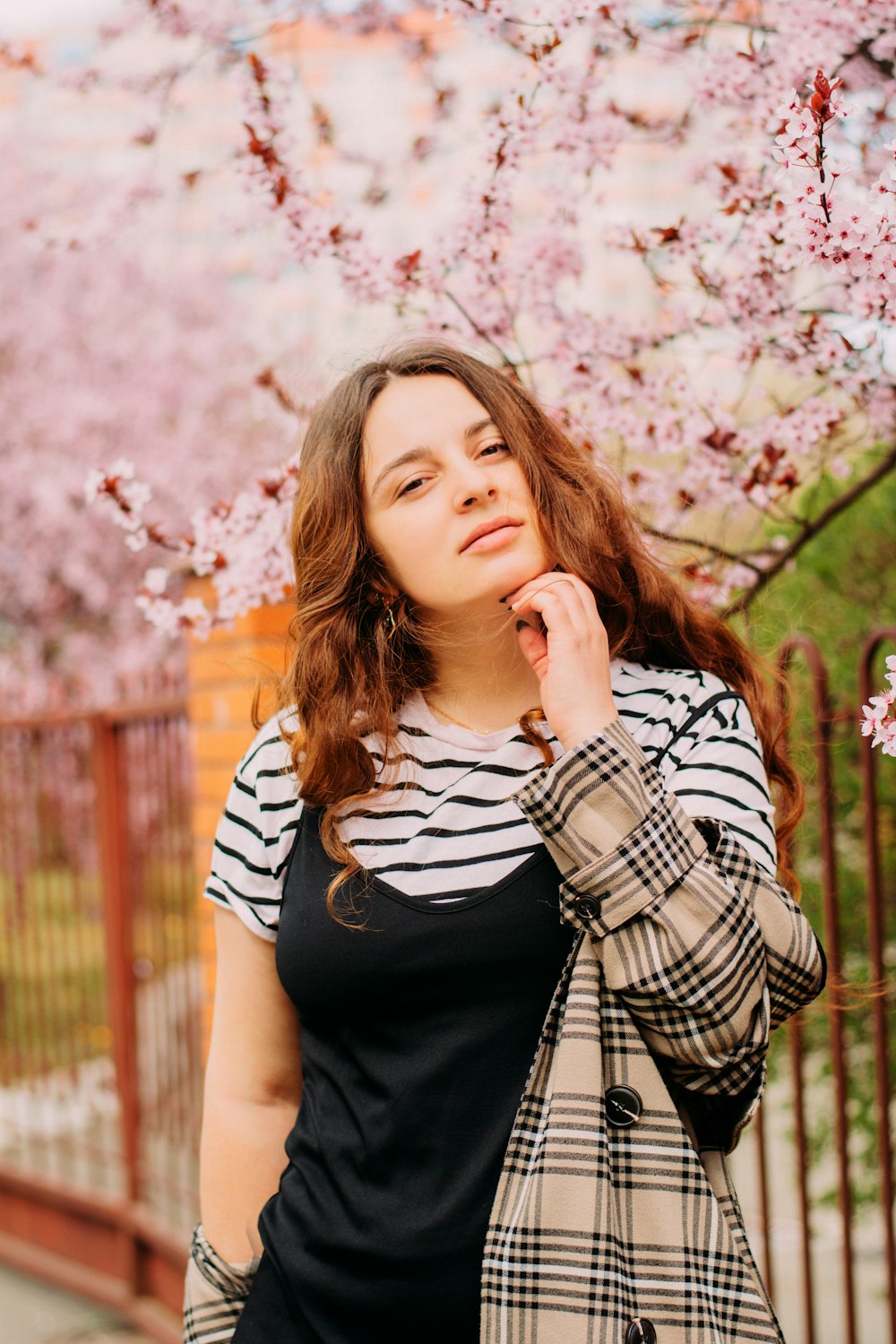 woman in black and white striped shirt standing near pink flowers during daytime