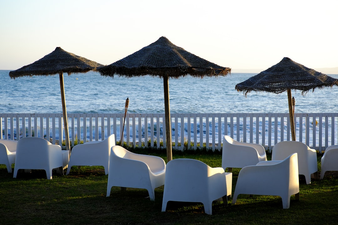 white plastic armchairs near brown wooden beach cottage