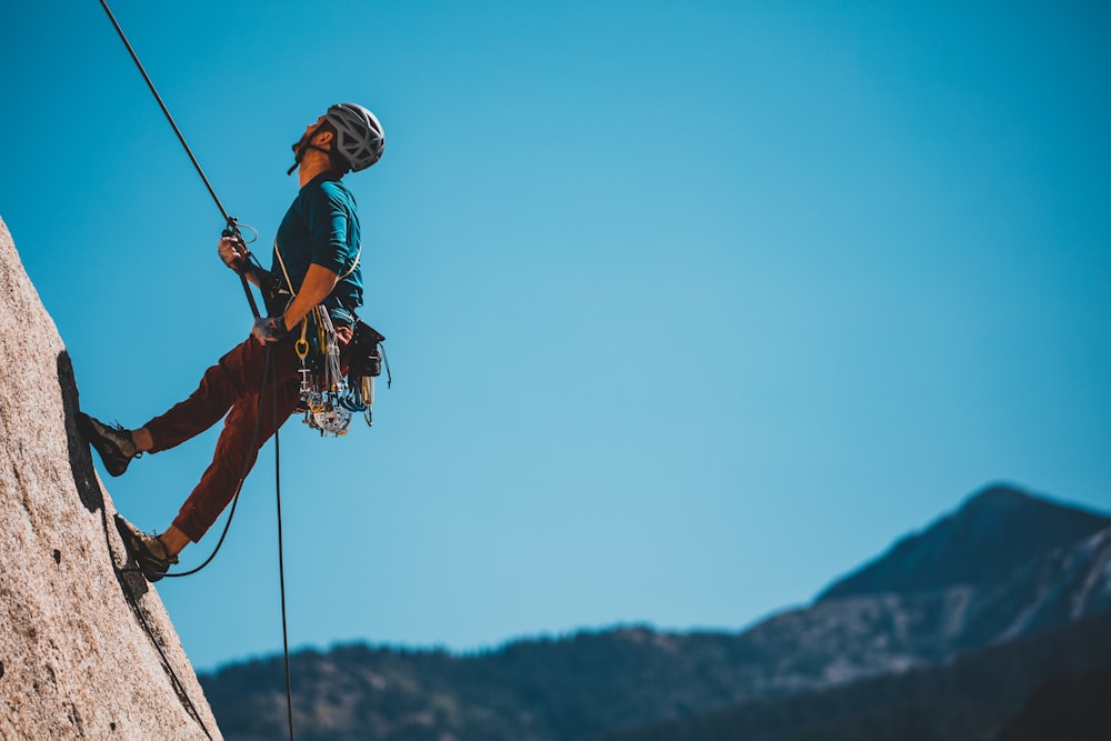 Homme en veste bleue et orange et casque noir sur un téléski noir et blanc