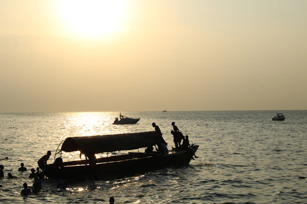 A serene sunset over the Arabian Sea with a small boat gently cruising near wild dolphins.