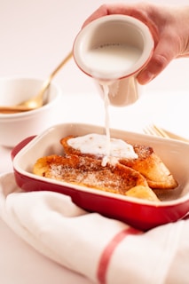 person pouring milk on white ceramic bowl