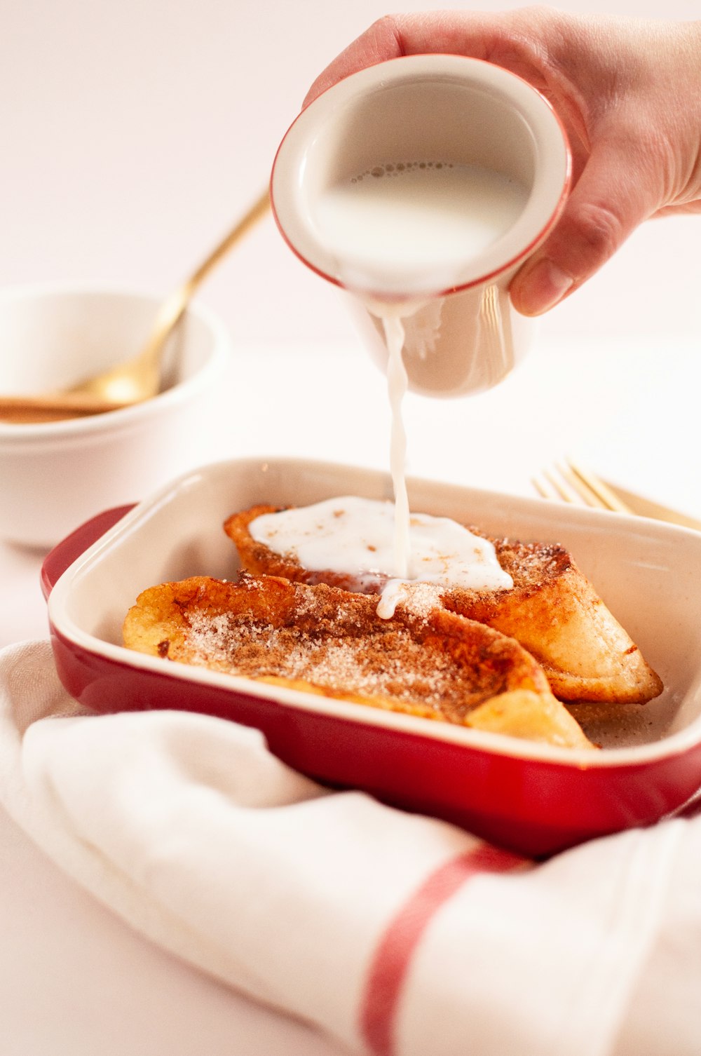 person pouring milk on white ceramic bowl