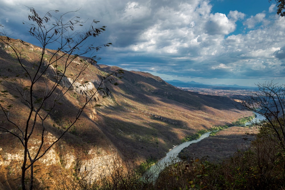 brown and green mountains under white clouds and blue sky during daytime