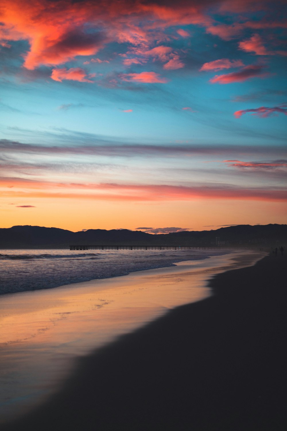 body of water near mountain during sunset