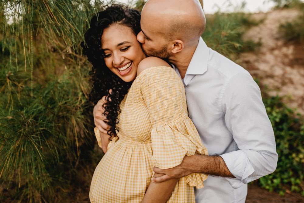 man in white dress shirt hugging woman in brown and white plaid dress