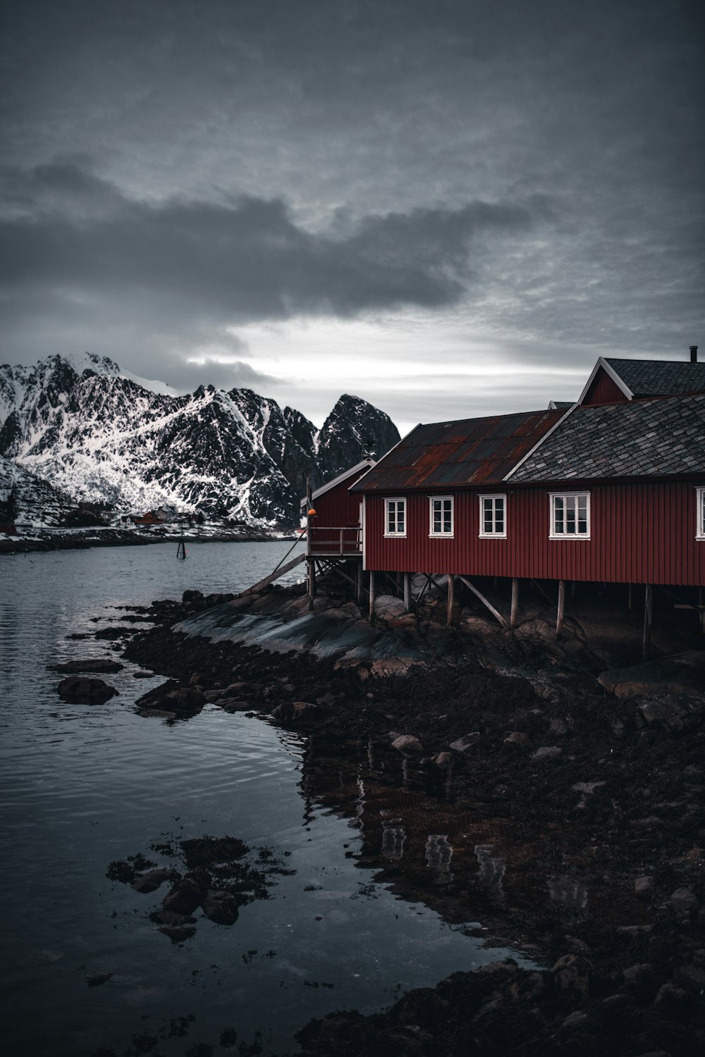 red wooden house near lake and snow covered mountain during daytime