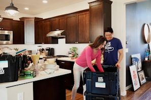 woman in pink long sleeve shirt standing beside kitchen sink
