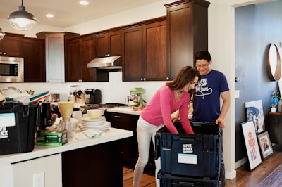 woman in pink long sleeve shirt standing beside kitchen sink