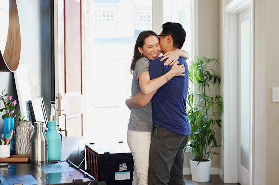 Warm photo of a friendly real estate agent warmly greeting a young couple at their new home.
