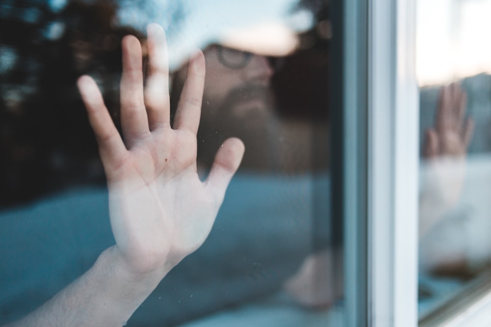 La mano de las personas en la ventana de vidrio