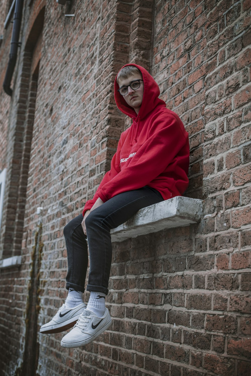 Woman in red hoodie and black pants sitting on brown brick wall during  daytime photo – Free Uk Image on Unsplash