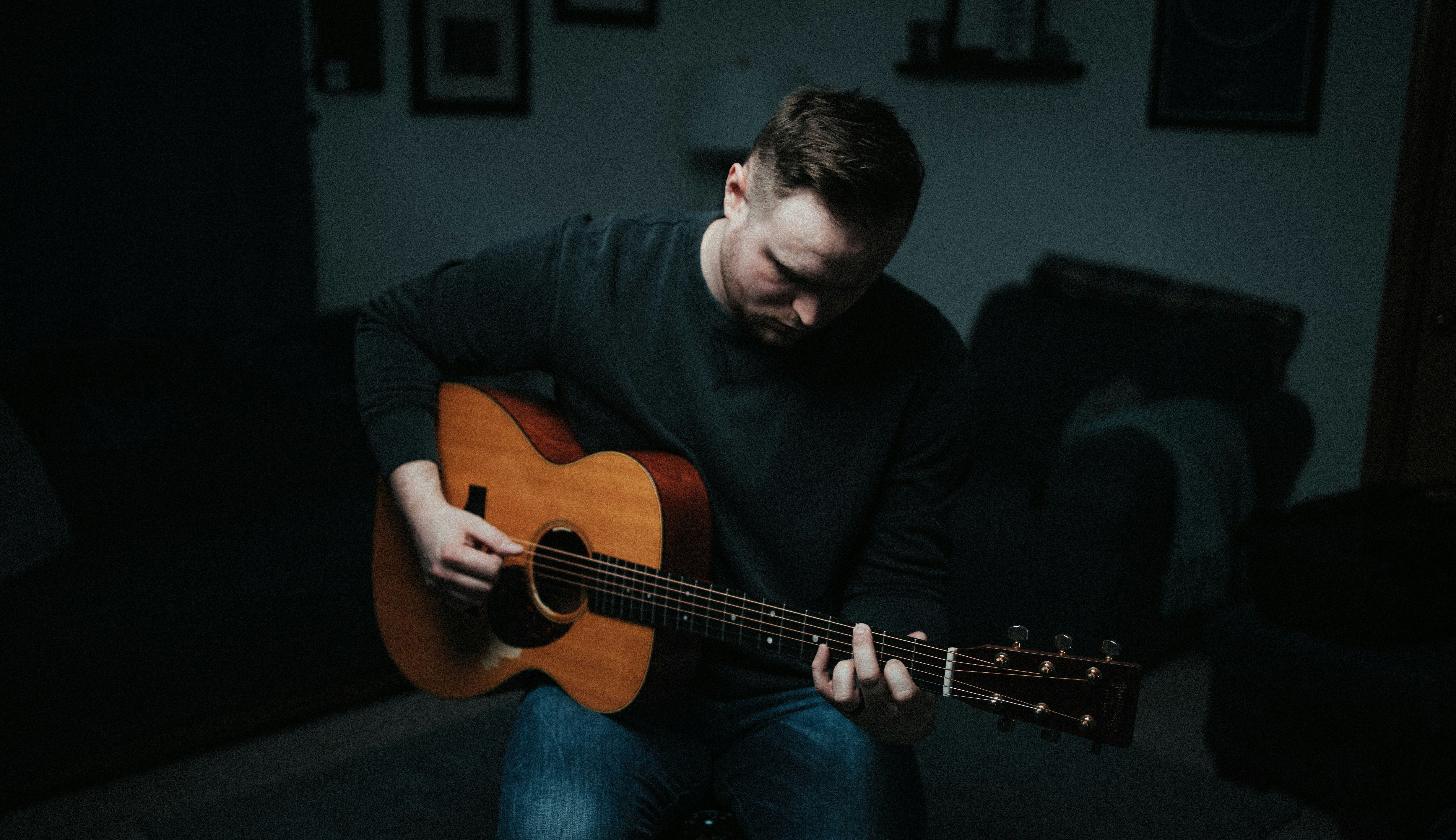 man in black long sleeve shirt playing brown acoustic guitar