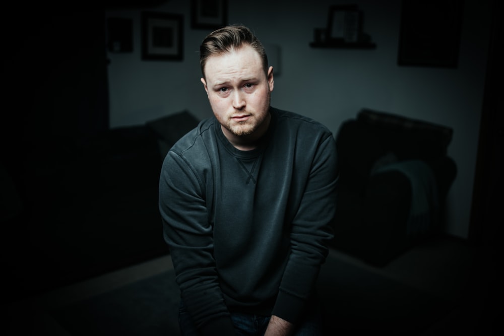 man in black long sleeve shirt sitting on black couch