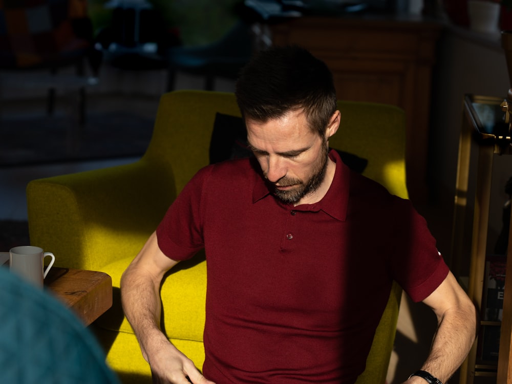 man in red polo shirt sitting on yellow chair