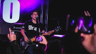 Musician performing live on stage with a smartphone displaying a QR code for digital tips.